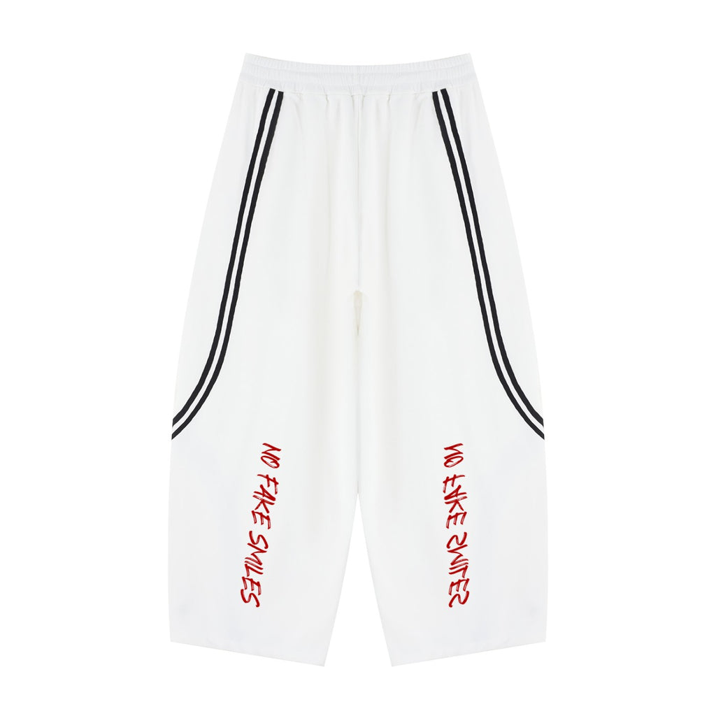No Fake Smiles white wide leg sweatpants with black side piping and red graphic text on the front legs.